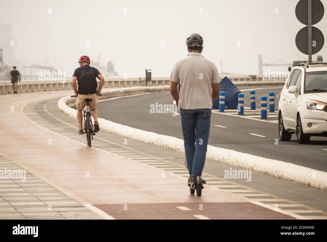 Ciclista e scooter elettrico sulla pista ciclabile separata dal traffico. Spagna Foto Stock