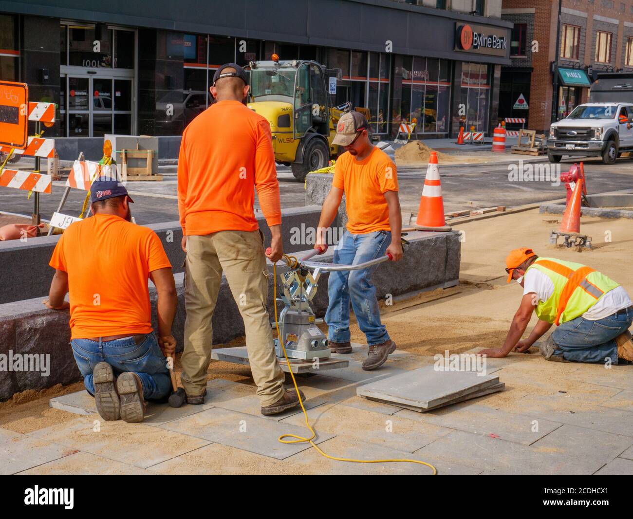 Lavoratori edili che utilizzano un sollevatore elettrico a ventosa per posizionare i blocchi di pavimentazione sul progetto di ricostruzione Lake Street. Oak Park, Illinois. Foto Stock