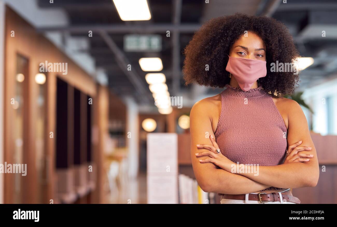 Ritratto di donna d'affari africana alla moda con maschera in ufficio. Foto Stock