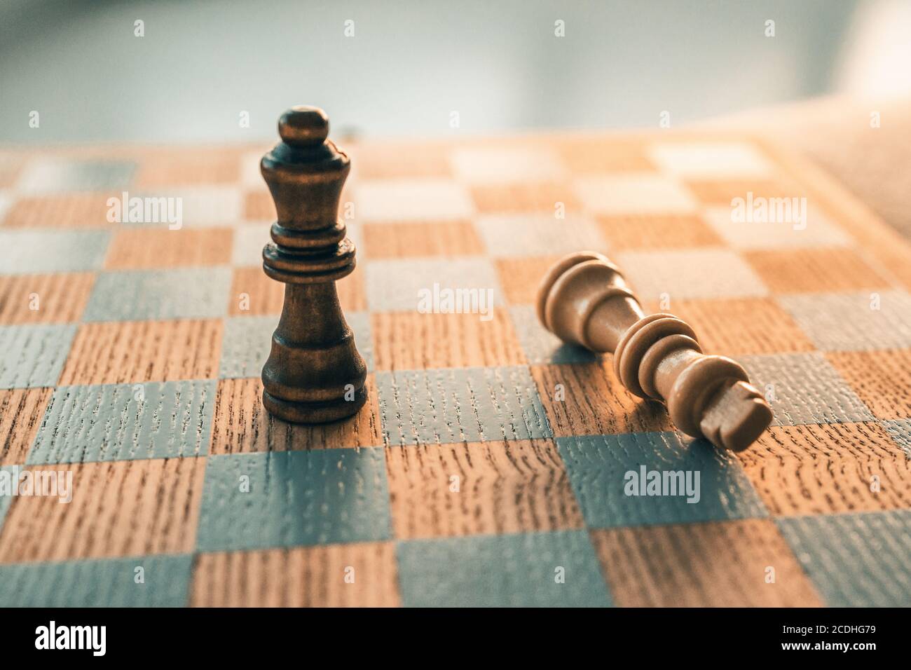 Concetto vincente del gioco degli scacchi. La vittoria si muove con l'ultimo pezzo in piedi su tavola di legno di scacchiera Foto Stock