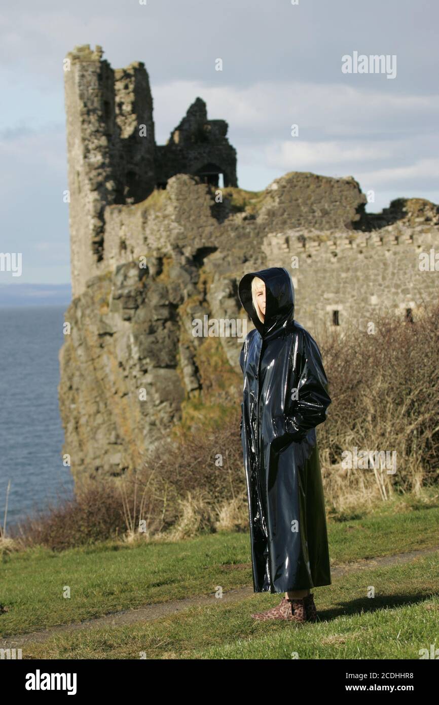 Ayrshire Coast, Scozia, caucasica donna bianca in lungo lucido cappotto nero con cappuccio cammina in modo enigmatico, Outlander posizione a Dunure Foto Stock