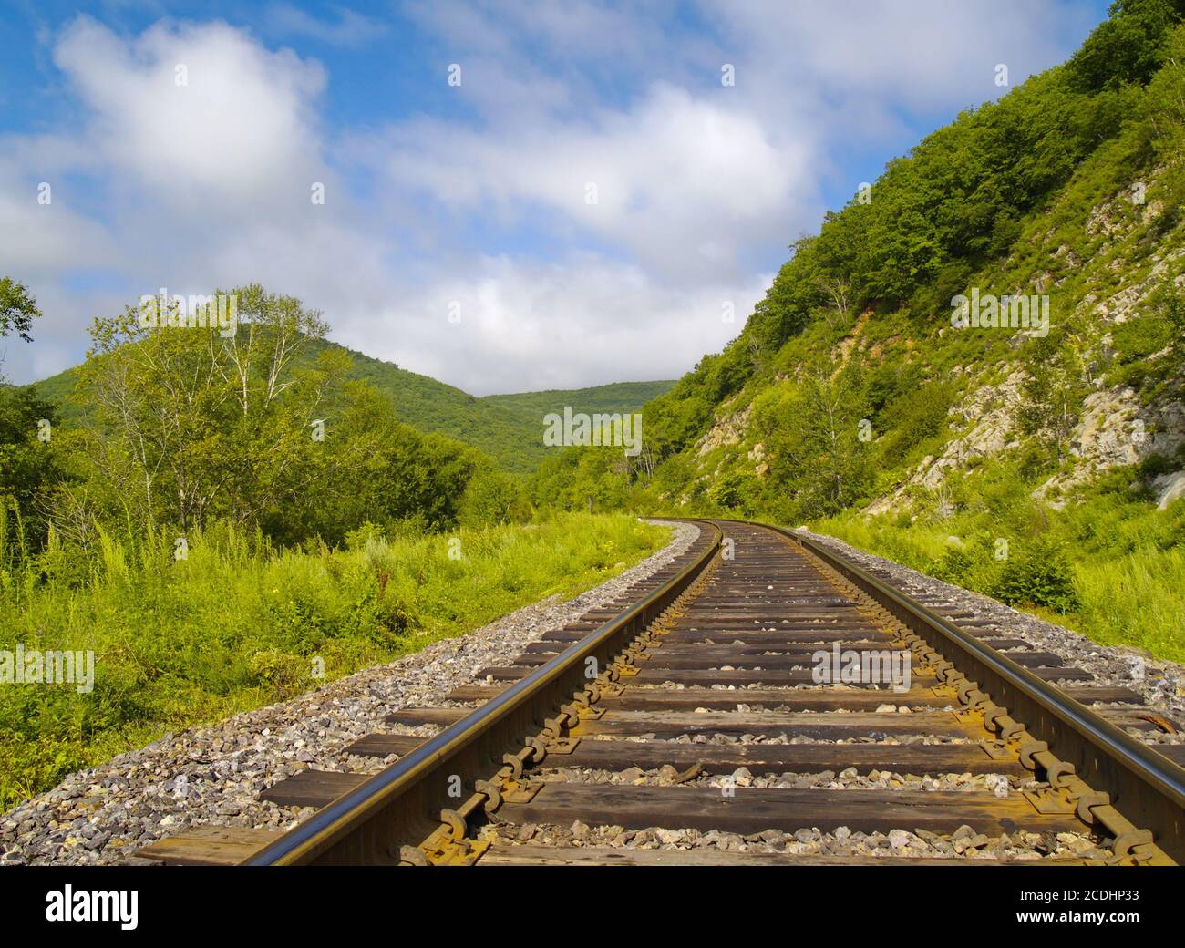 Anno paesaggio con linea ferroviaria, colline e cielo nuvoloso Foto Stock