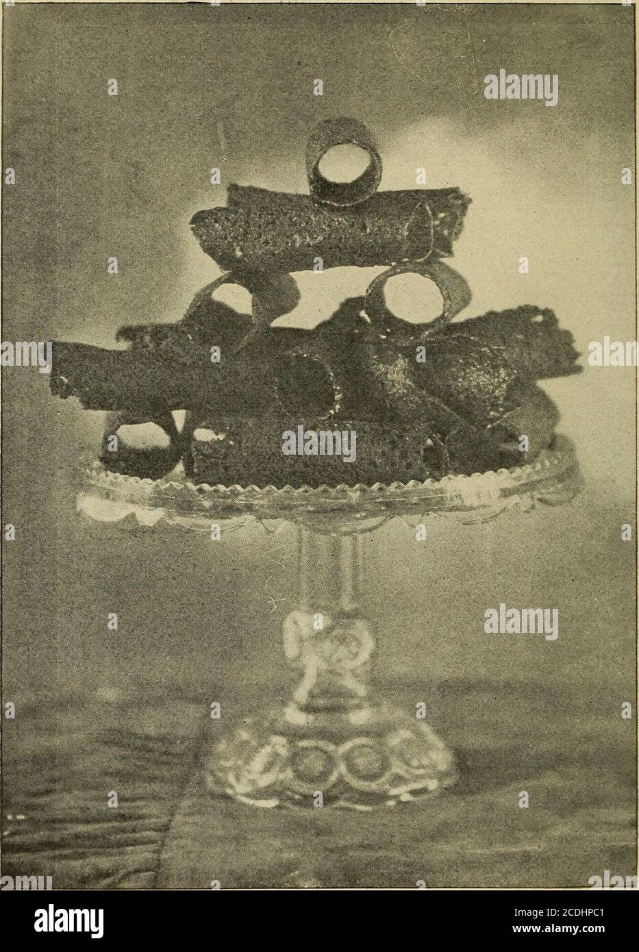 . L'orgoglio della famiglia; la gestione completa dei panettieri . Copyright, 1900, di M. A. & K. M. Heinzer. BOTTONI DI BRANDY. 68 Snap Brandy. I tazza di zucchero. 1 tazza di burro. Tazza di melassa di?J. 2 tazze di farina. ?J cucchiaino di zenzero.?J cucchiaino di cannella.•| cucchiaino di allspice. COME MESCOLARE. Strofinare il burro, lo zucchero e le spezie insieme, quindi aggiungere le temolasse e mescolare bene, quindi aggiungere la farina e mescolare bene. COME CUOCERE. Mettere un tubo di mezzo pollice in un sacchetto di ornamento, mettere la spremitura nel sacchetto, quindi premere attraverso il tubo eformare anelli la dimensione di una piccola tazza di tè su un panab ingrassato Foto Stock