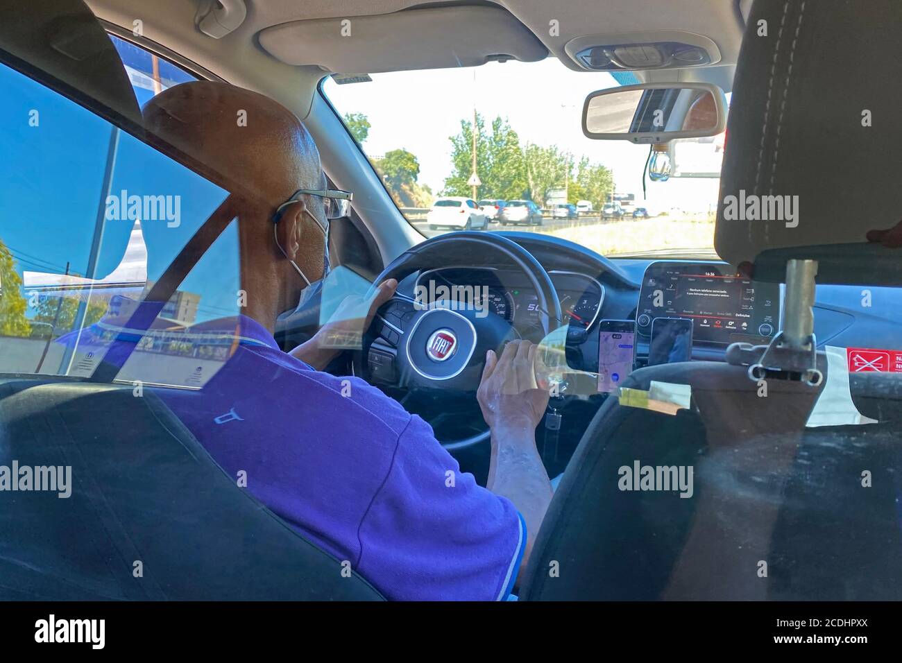 Un conducente del fornitore di mobilità ORA LIBERO al volante, indossa una maschera facciale, maschera, un pannello in plexiglass separa i sedili anteriori e posteriori. Misurare per evitare l'infezione da Coronavirus Covid-19. | utilizzo in tutto il mondo Foto Stock