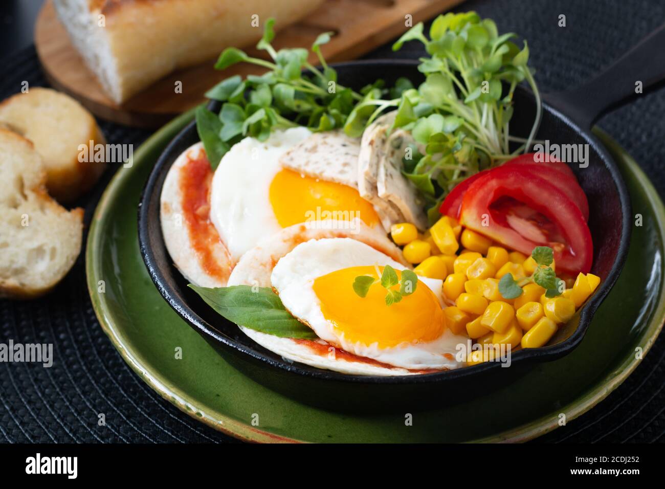 Cibo sano concetto di colazione super uova fritte e insalata micro-verde Con mais e pomodoro in padella di ferro Skillet con copia spazio Foto Stock
