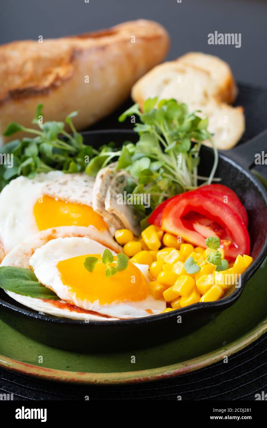 Cibo sano concetto di colazione super uova fritte e insalata micro-verde Con mais e pomodoro in padella di ferro Skillet con copia spazio Foto Stock