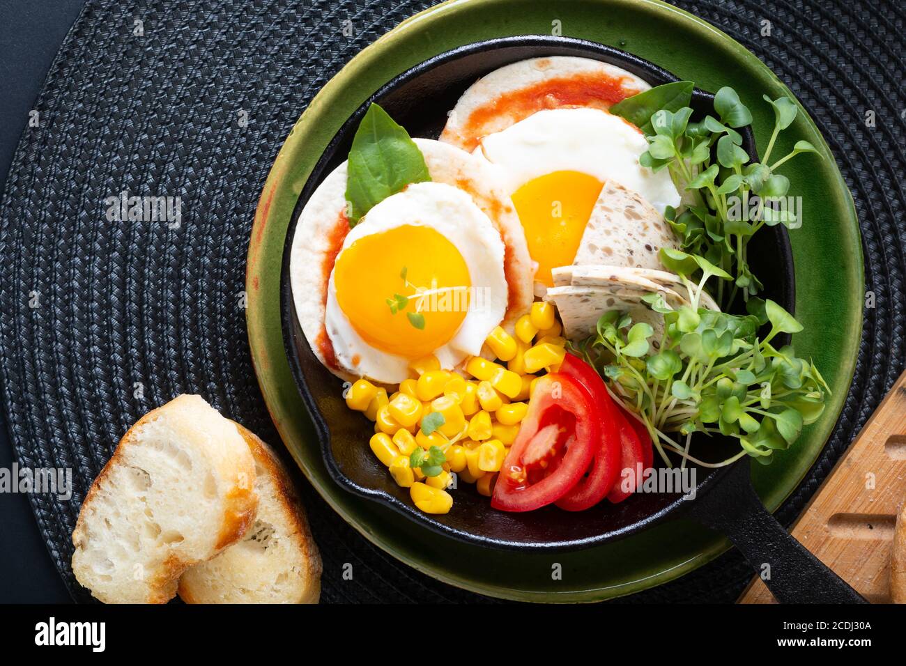 Cibo sano concetto di colazione super uova fritte e insalata micro-verde Con mais e pomodoro in padella di ferro Skillet con copia spazio Foto Stock