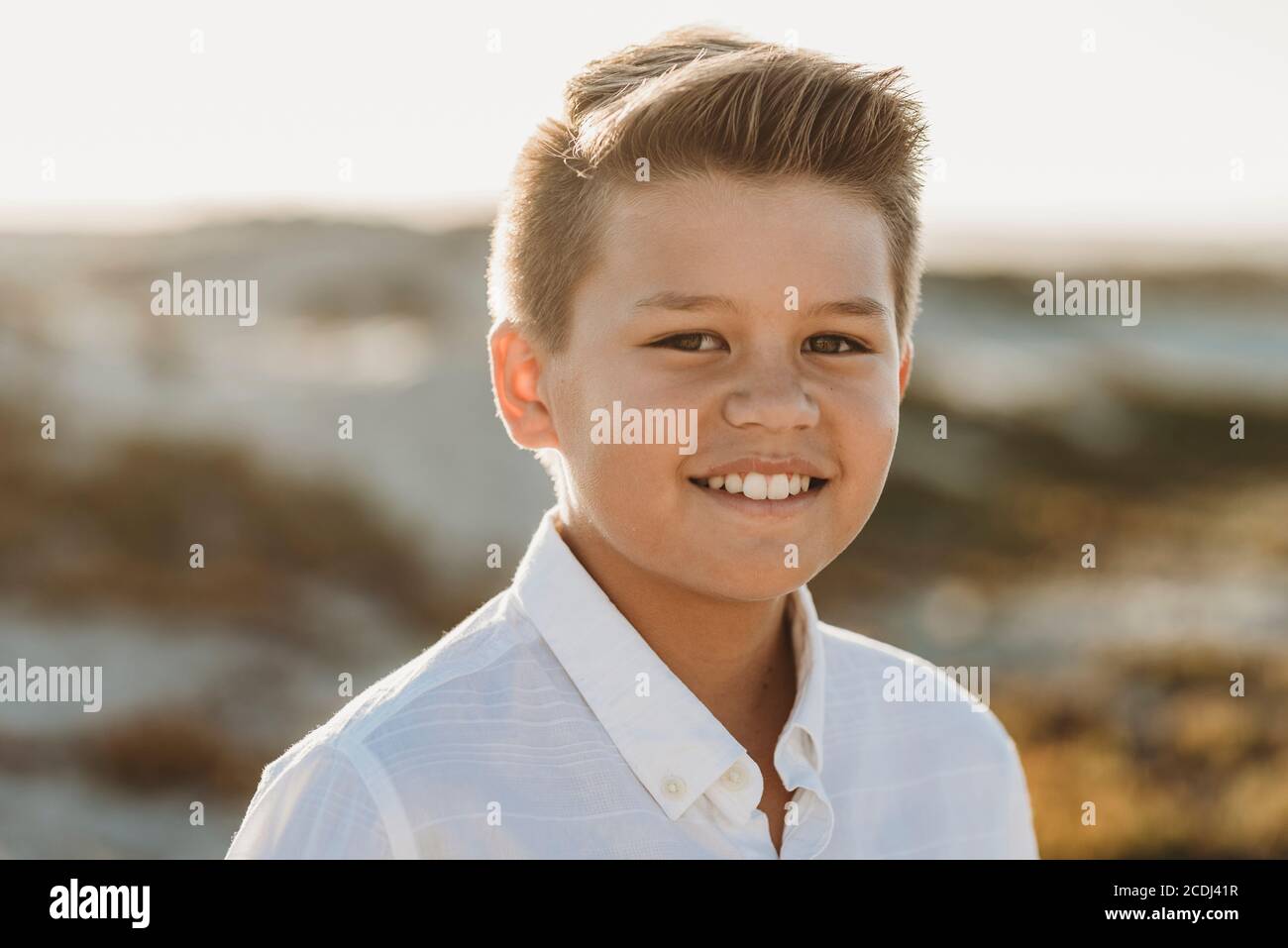 Ragazzo che indossa una camicia bianca button-down, sorridente e tagliato in forma pulita Foto Stock
