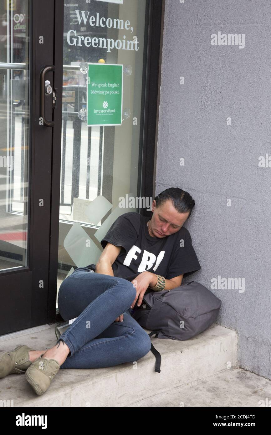 Donna apparentemente è passata fuori all'ingresso di una banca a Greenpoint, Brooklyn con una bottiglia di liquore tra le gambe. Foto Stock