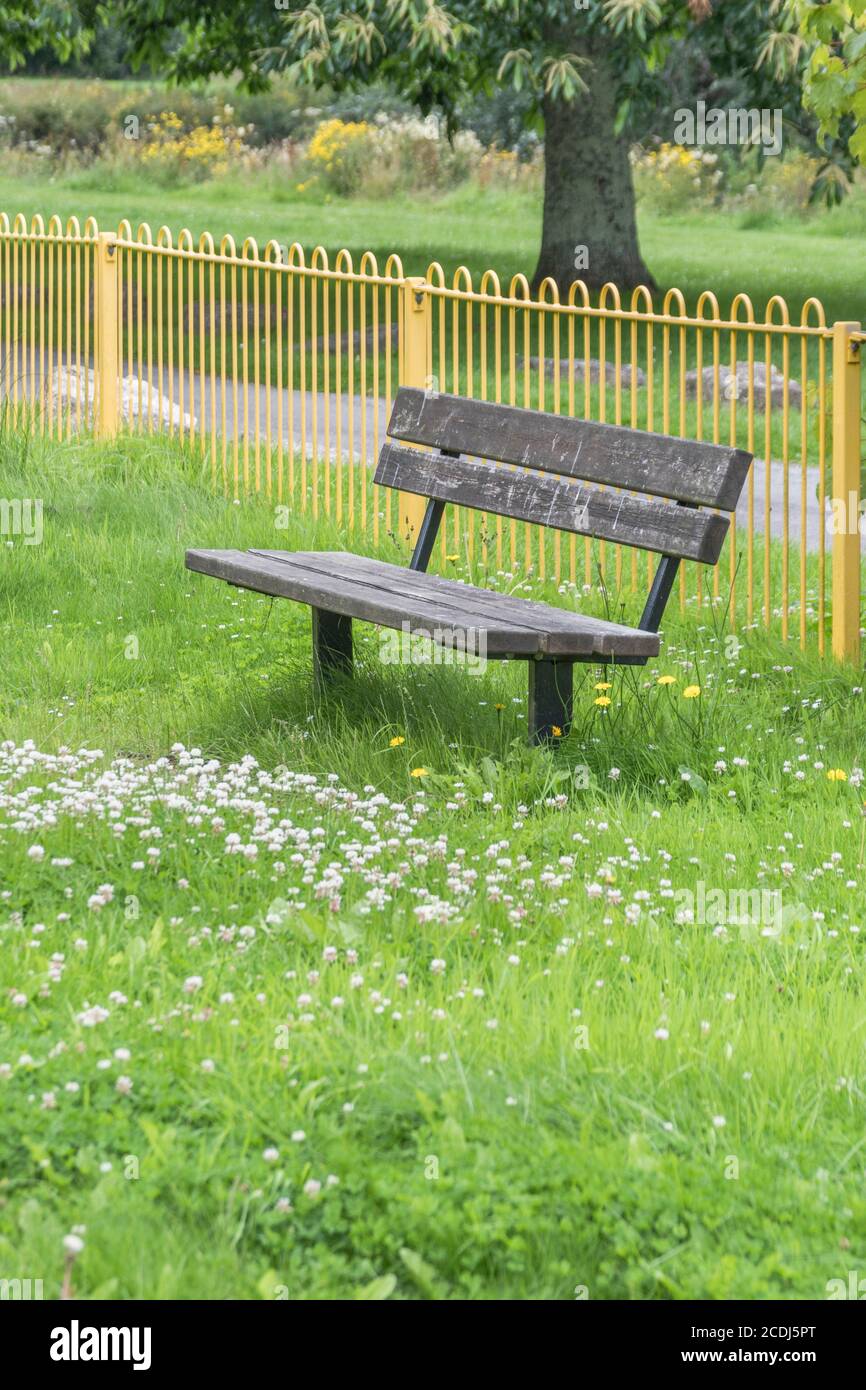 Sedile pubblico solitario/panca in un parco giochi per bambini vuoto di persone durante il blocco Covid del Regno Unito. Spazio pubblico desertato, panca vuota del parco nel Regno Unito. Foto Stock