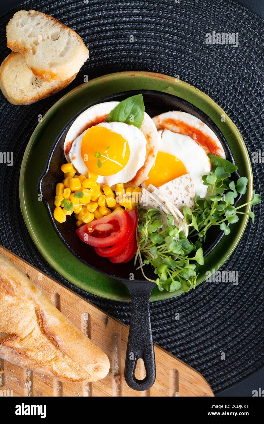 Cibo sano concetto di colazione super uova fritte e insalata micro-verde Con mais e pomodoro in padella di ferro Skillet con copia spazio Foto Stock