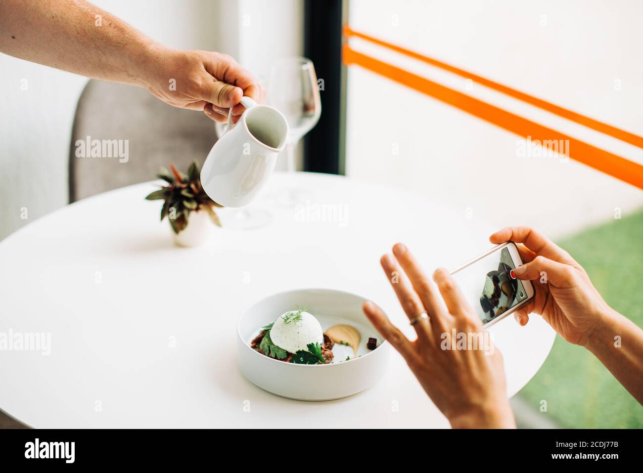 Le mani scattano le foto del cibo con lo smartphone mentre il cameriere serve pasto Foto Stock