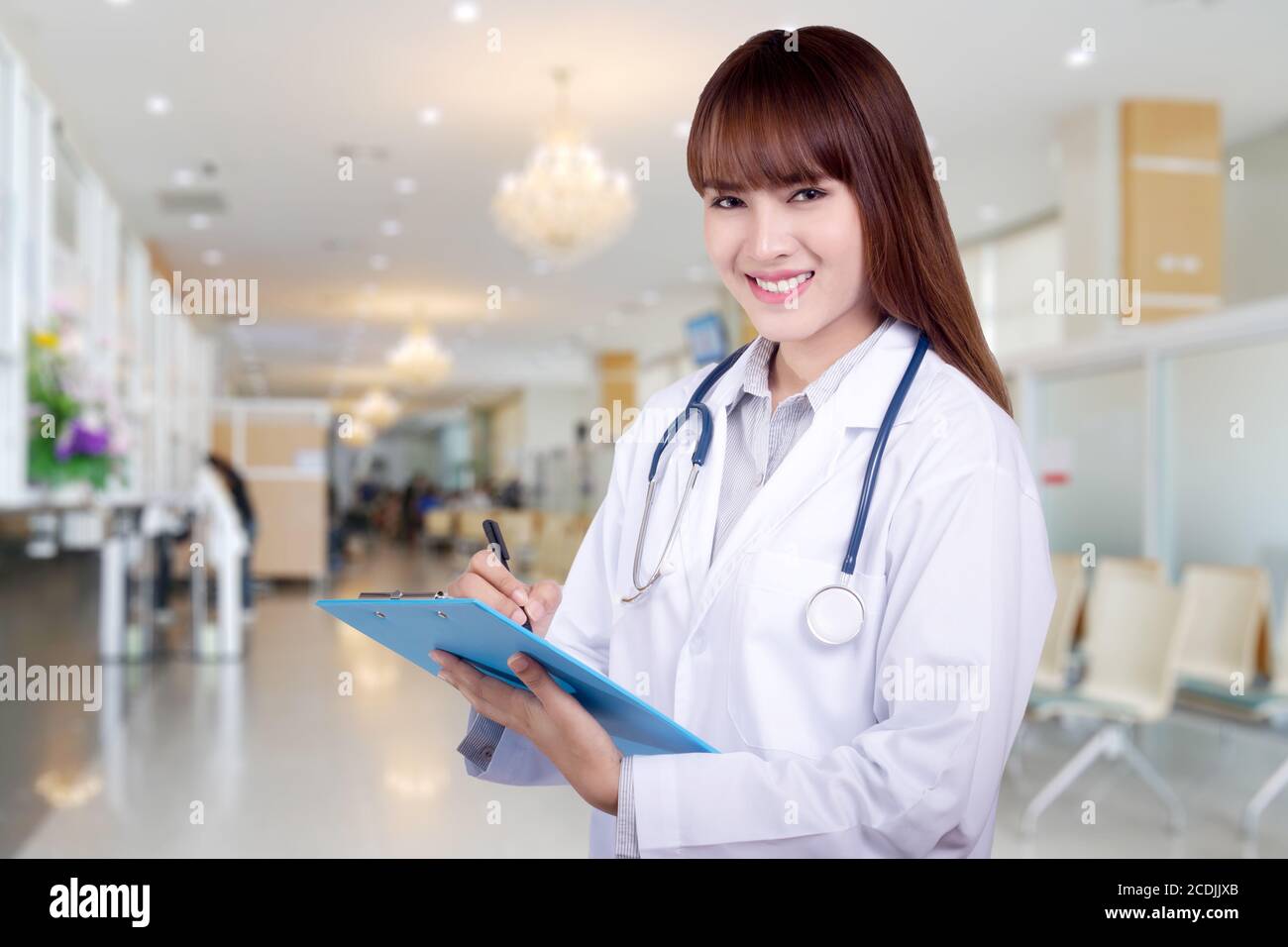 Dettaglio di una giovane donna asiatica dottore in possesso di una clipboard in piedi sullo sfondo dell'ospedale. Concetto di assistenza sanitaria Foto Stock
