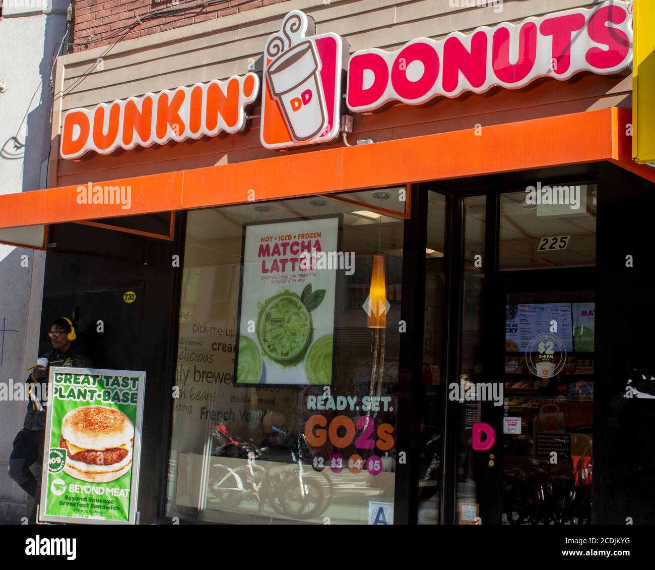 Esterno di un negozio Dunkin Donuts a Chelsea, Manhattan con cartelli che pubblicizzano la loro pianta a base di hamburger senza carne e matcha lattes Foto Stock