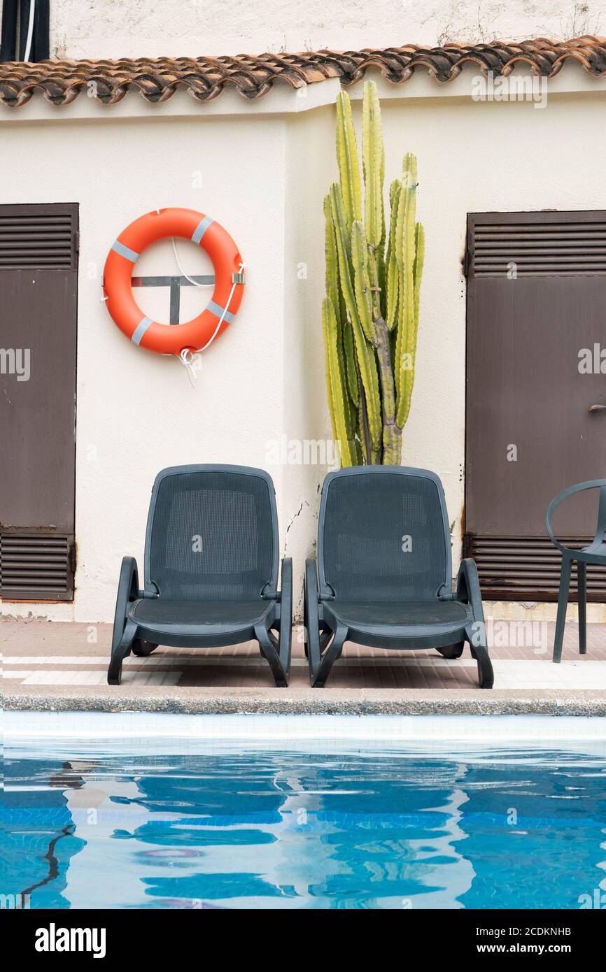 Sedie a sdraio vuote accanto alla piscina in un hotel vuoto a causa di pandemie di coronavirus. Recessione dell'economia turistica. Foto Stock