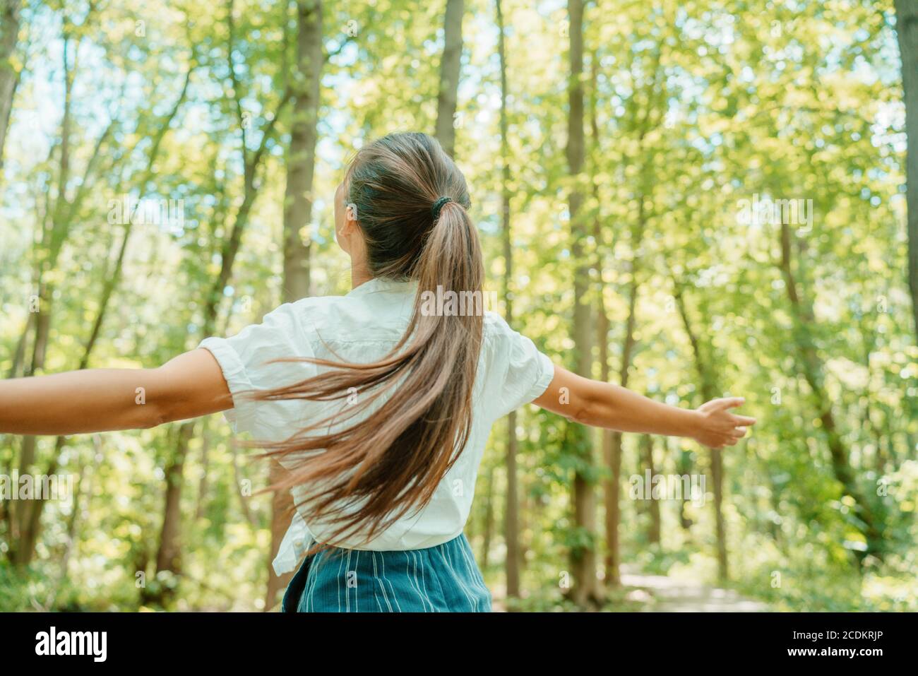 Donna felice in foresta con le braccia aperte da dietro respirare aria pulita. Ambiente, nessun inquinamento sano stile di vita naturale. Spirito libero in Foto Stock