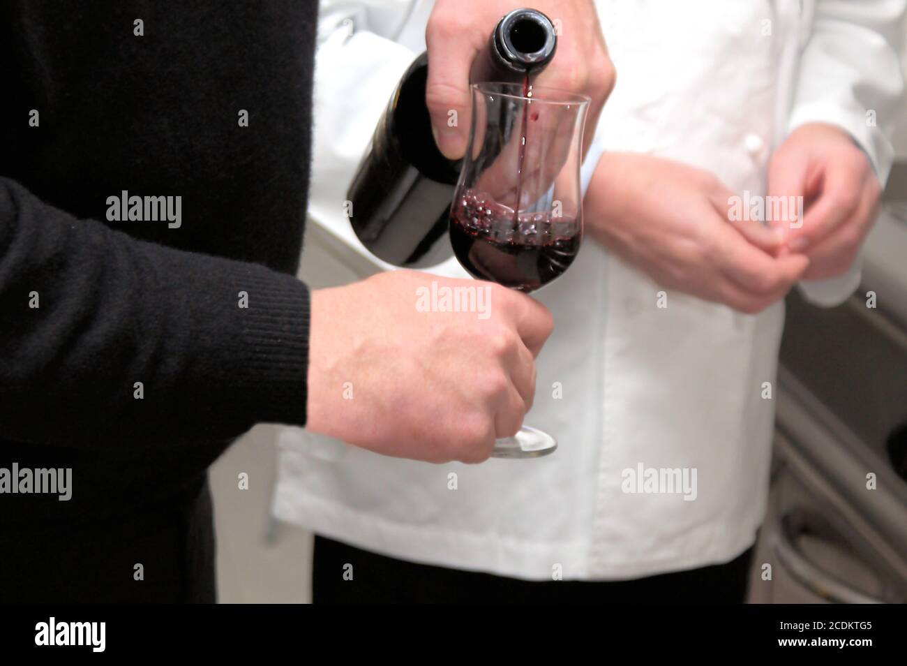 sommelier versando vino rosso in un bicchiere, parti del corpo Foto Stock