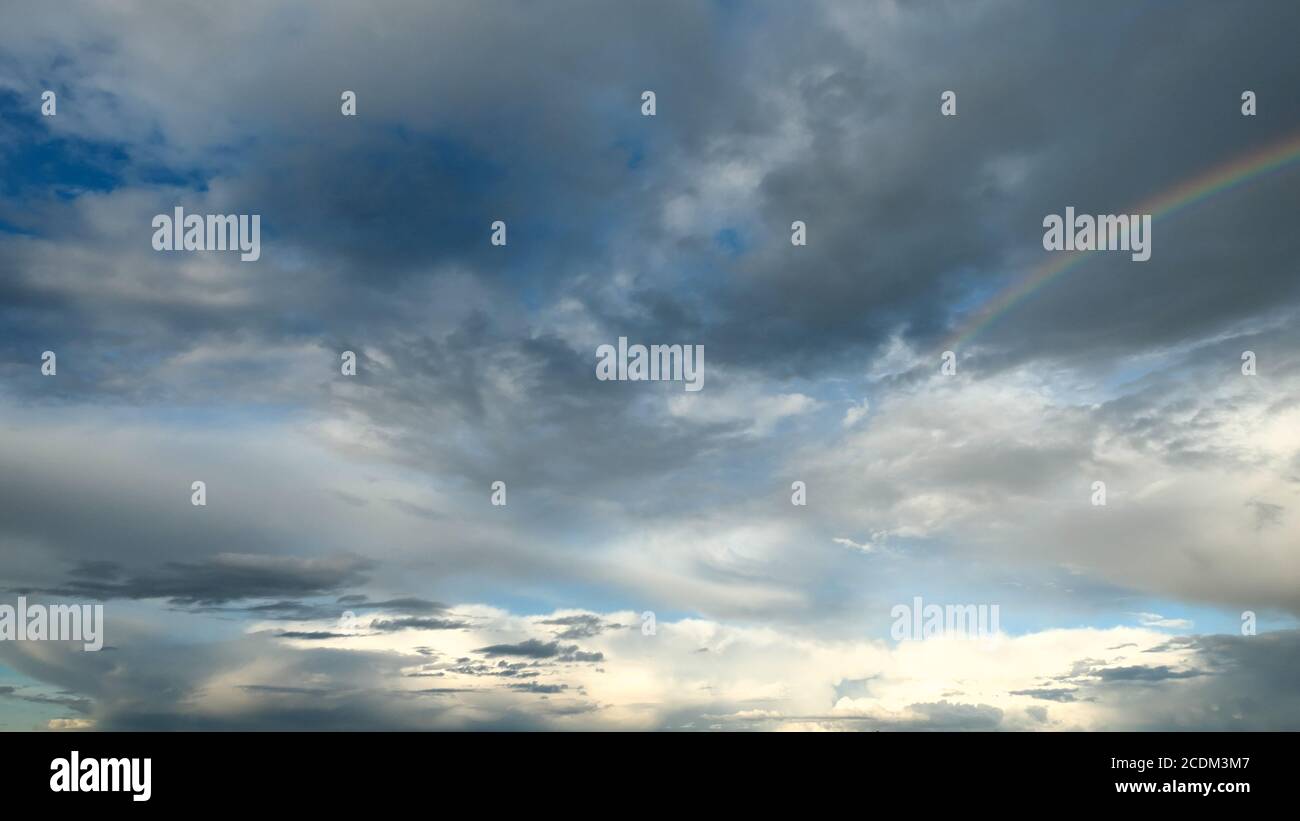 Incredibile cielo drammatico. Il tempo nuvoloso si fa piovoso. Cumulonimbus in atmosfera con arcobaleno. Foto Stock