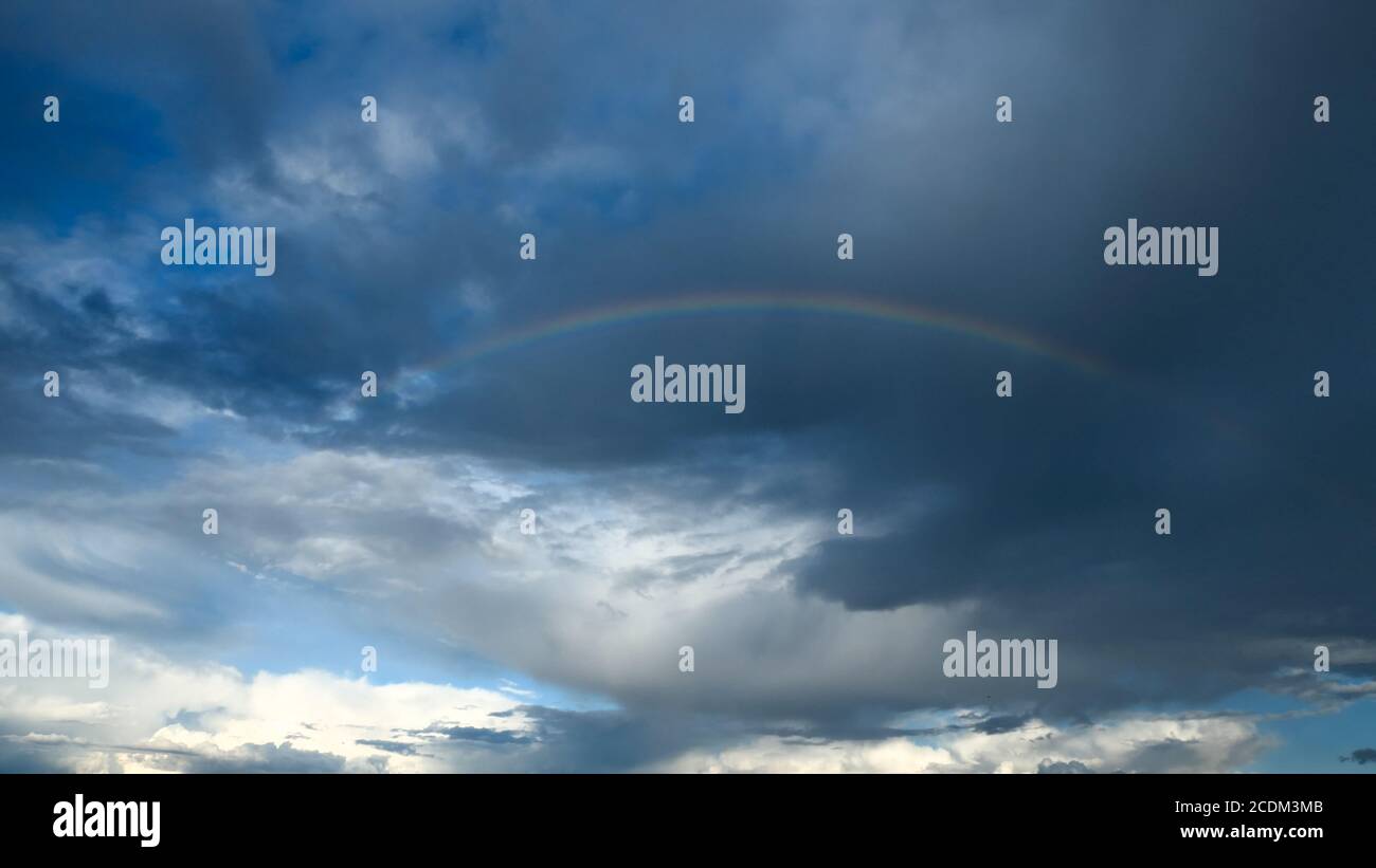 Incredibile cielo drammatico. Il tempo nuvoloso si fa piovoso. Cumulonimbus in atmosfera con arcobaleno. Foto Stock