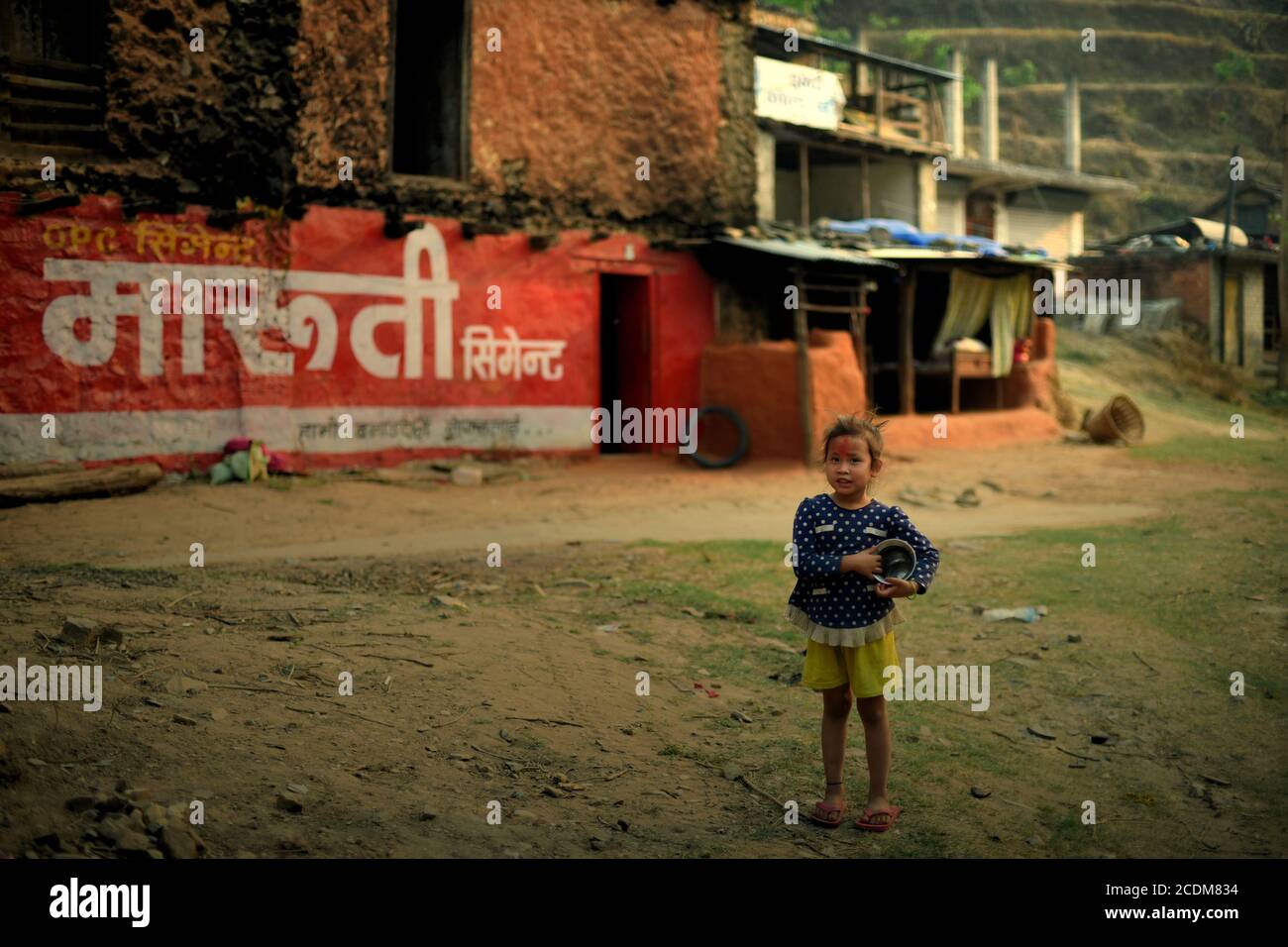 Ritratto di un bambino in piedi sulla strada che porta un contenitore d'acqua mentre presta attenzione ad un veicolo nella provincia di Gandaki Pradesh in Nepal. Foto Stock