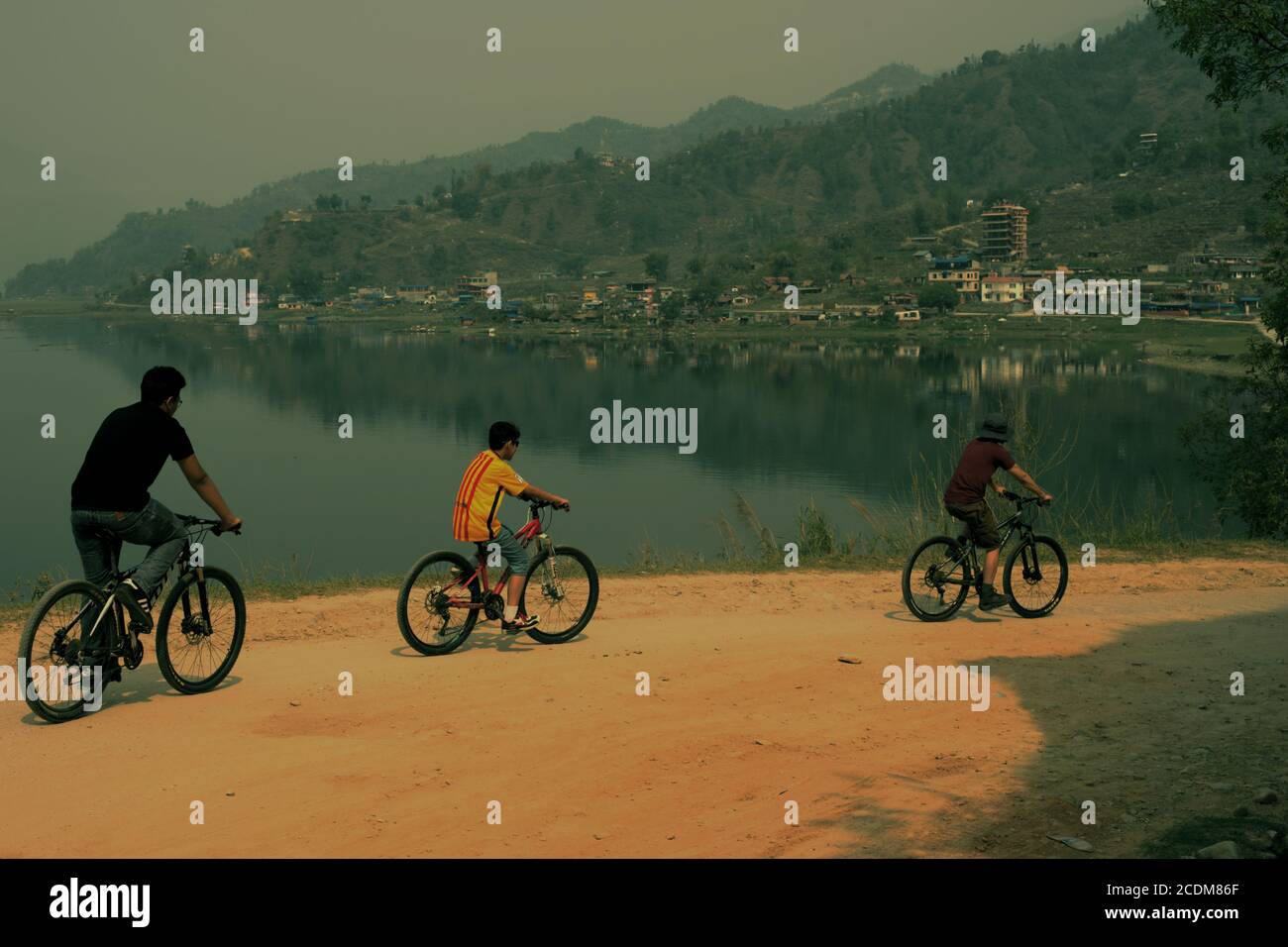Una famiglia in bicicletta lungo il lago Phewa vicino a Pokhara nel distretto di Kaski, Gandaki, Nepal. Il lago Phewa è uno dei laghi più ristretti dell'Asia meridionale. Foto Stock