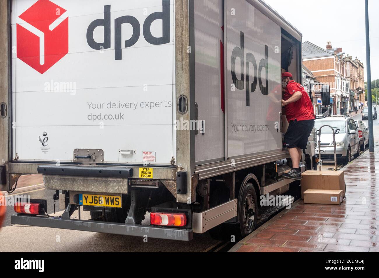 Un conducente di consegna DPD scarica alcune scatole di cartone per consegnarlo al cliente. Foto Stock