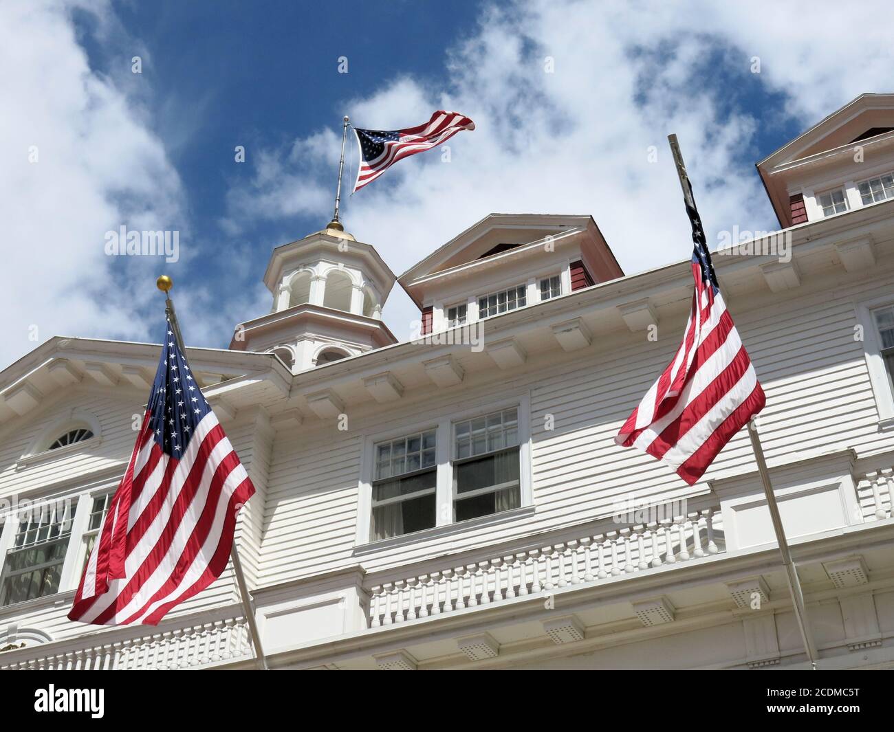 Tre bandiere statunitensi sfogano dal piano superiore ornato dello storico Stanley Hotel di Estes Park, Colon. Foto Stock