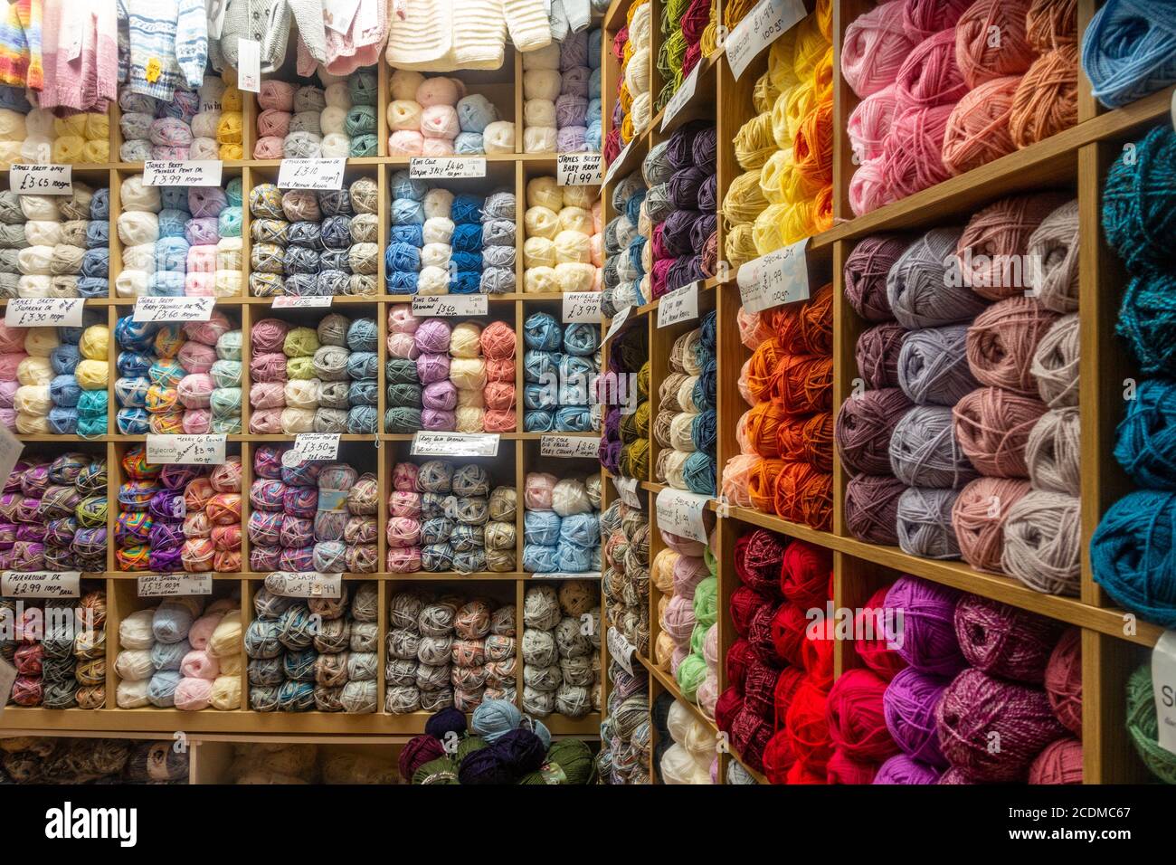 Palle di lana di maglia colorata disposte su scaffale in vendita in un negozio. Foto Stock