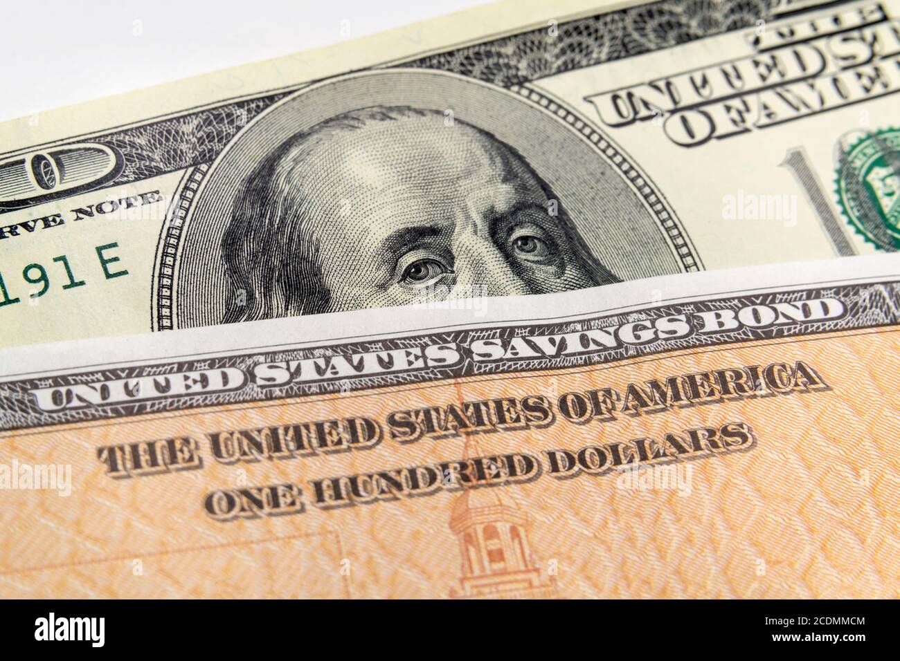 Macro vista di Benjamin Franklin sul conto di cento dollari che guarda sopra la parte superiore di un'obbligazione di risparmio degli Stati Uniti. Foto Stock
