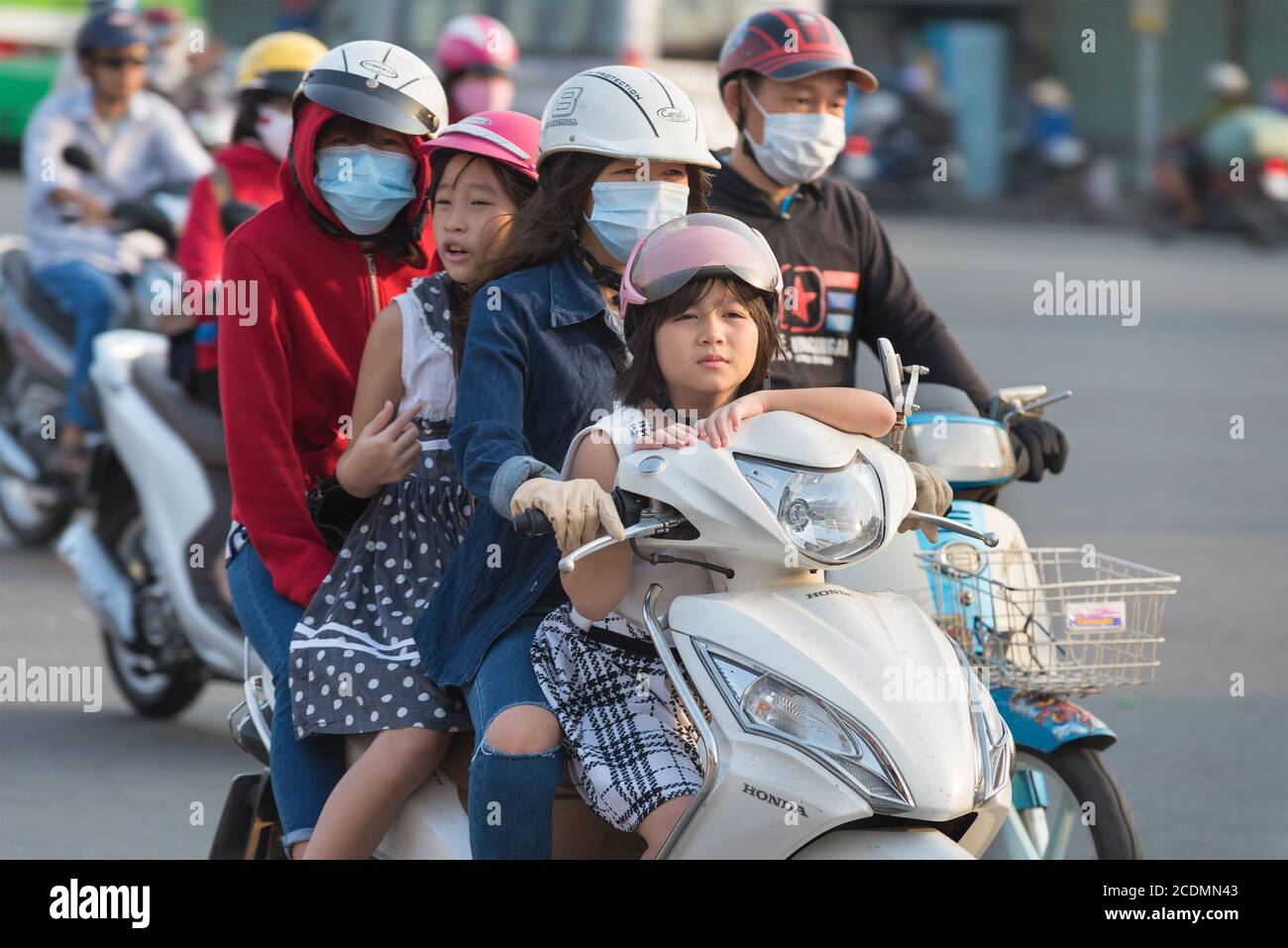 Motociclista vietnamita guida tre persone in più Foto Stock
