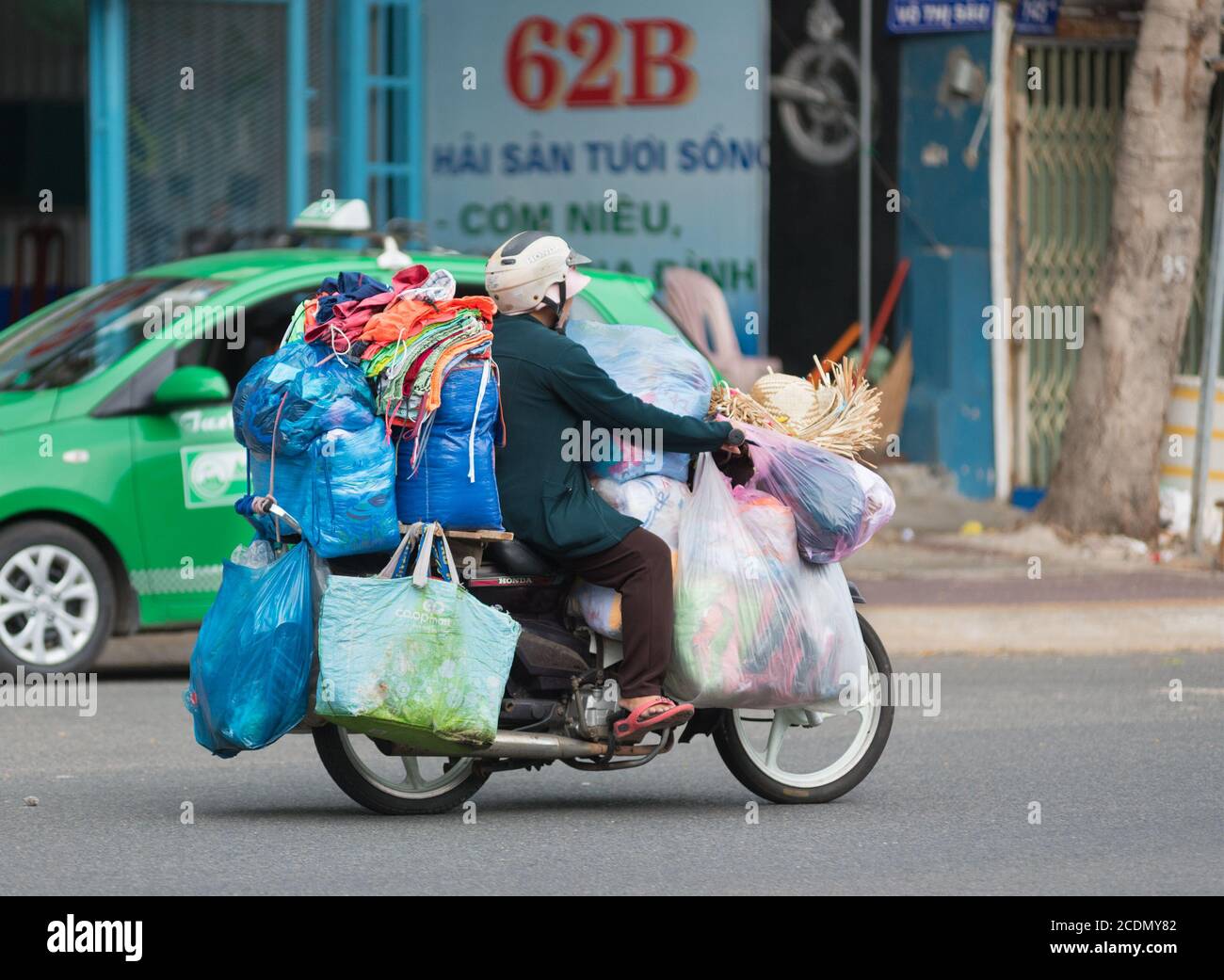 Motociclista vietnamita guida il carico Foto Stock