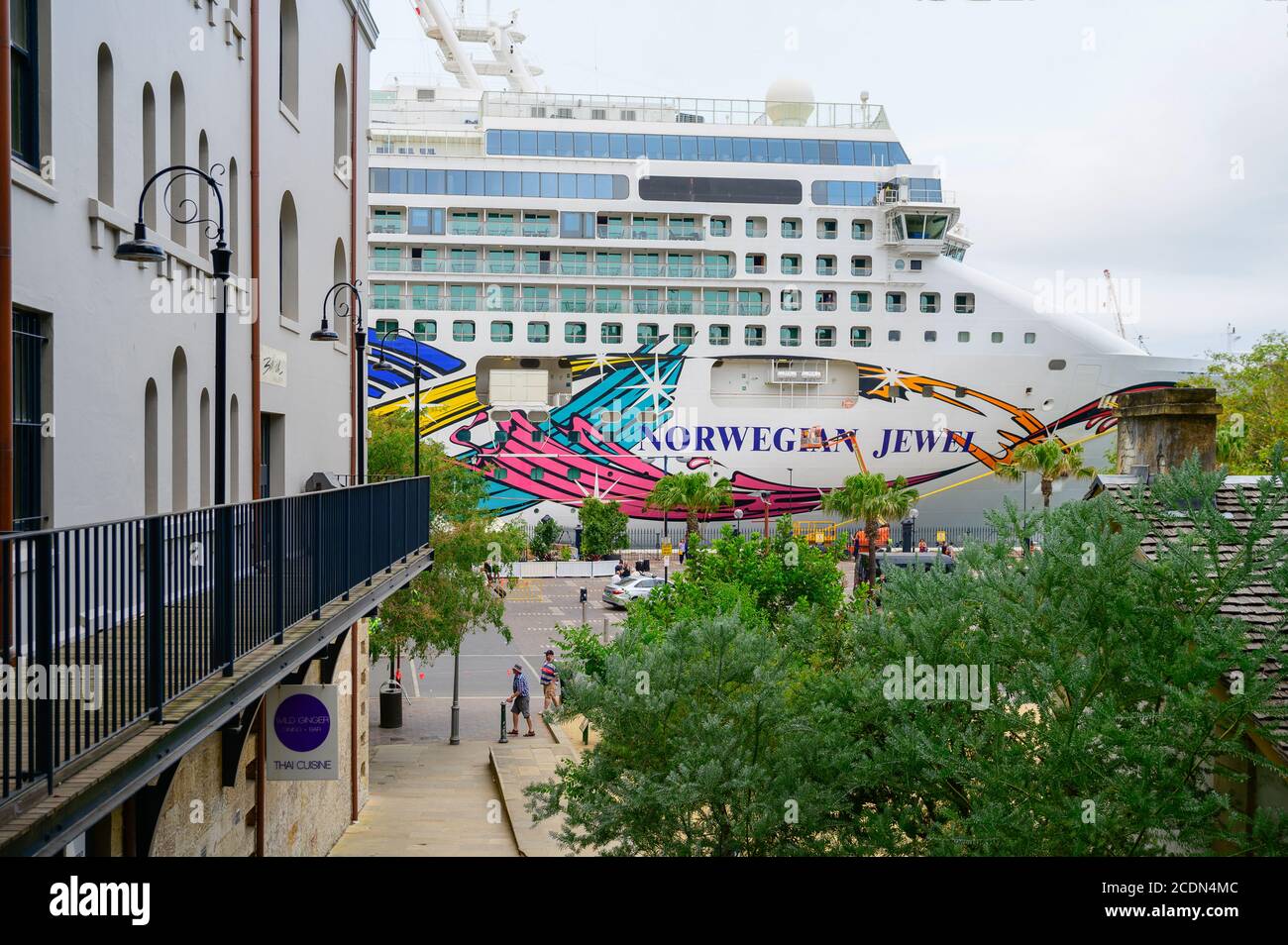 Vista di Circular Quay dalle rocce e norvegese Jewel Lo sfondo della nave da crociera si offusca in un pomeriggio estivo nuvoloso Foto Stock