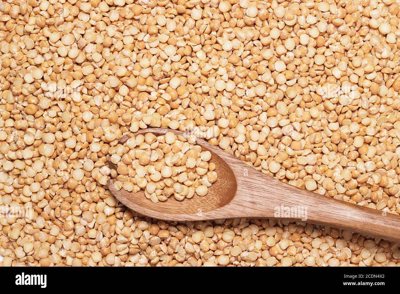 cucchiaio di legno marrone su fondo piselli asciutti Foto Stock