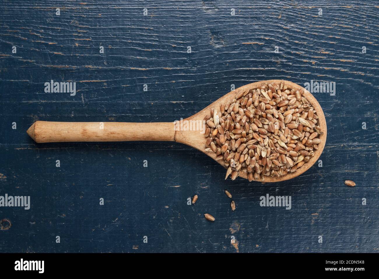 cucchiaio di legno pieno di raccolti sulla tavola blu Foto Stock