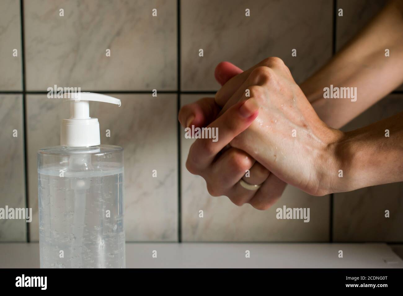 Donna che usa l'igienizzatore per le mani. L'azione di strofinare l'igienizzatore per le mani su entrambe le mani. Foto Stock