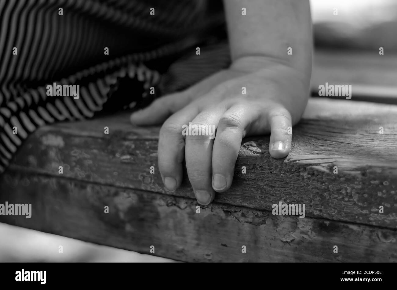 Primo piano di una mano femminile su una panchina di parcheggio. Una donna adulta si siede da sola su una panchina del parco. Amore e concetto di relazione. Messa a fuoco selettiva. Foto Stock