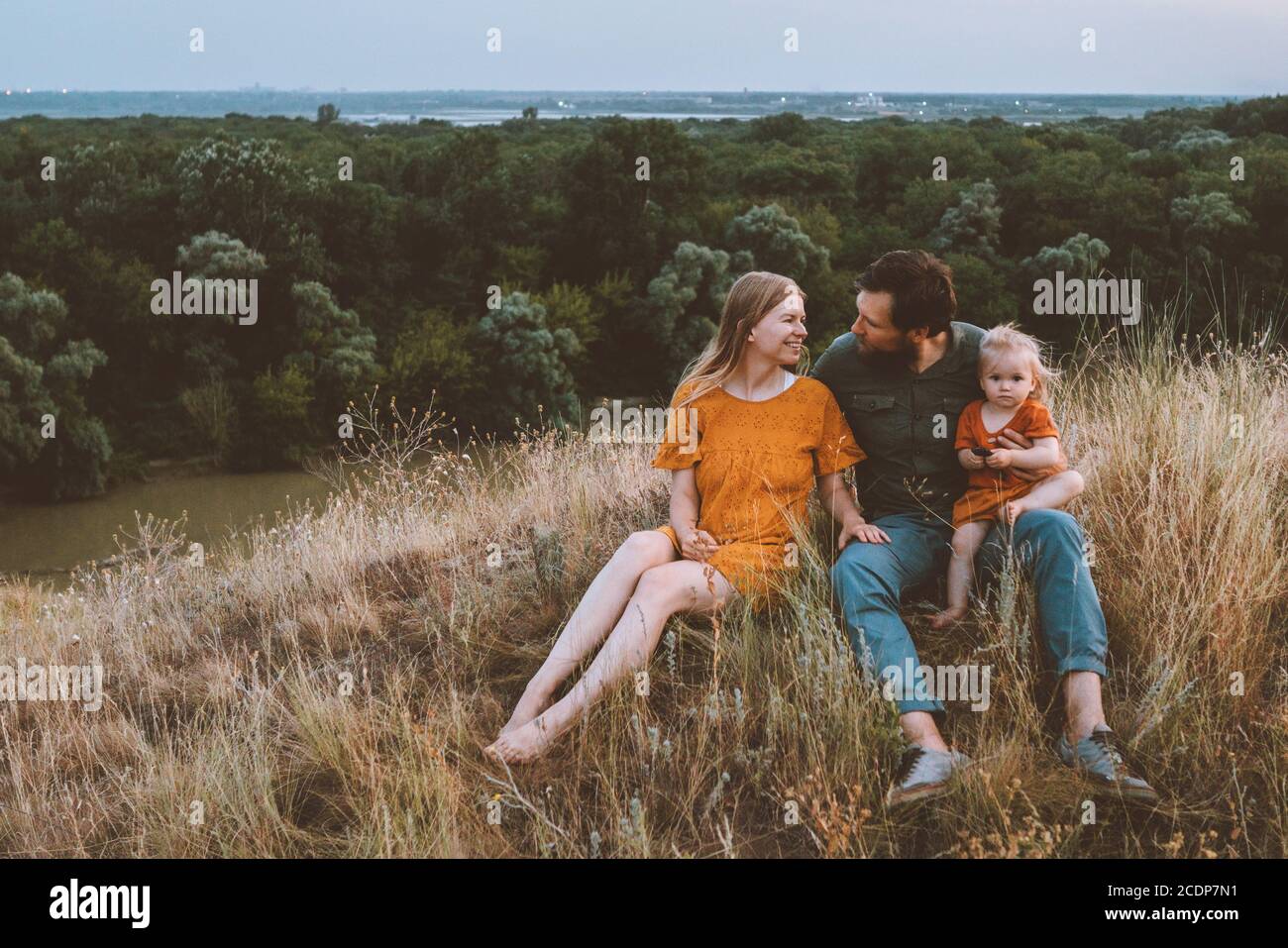 Famiglia madre e padre con bambino al picnic genitori all'aperto con il bambino che si rilassa sull'erba viaggi stile di vita estate week-end rurale natura Foto Stock