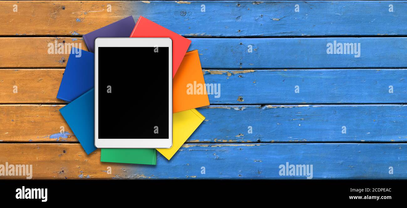 tablet, libri in colori arcobaleno sul tavolo dalle vecchie tavole, vista frontale Foto Stock