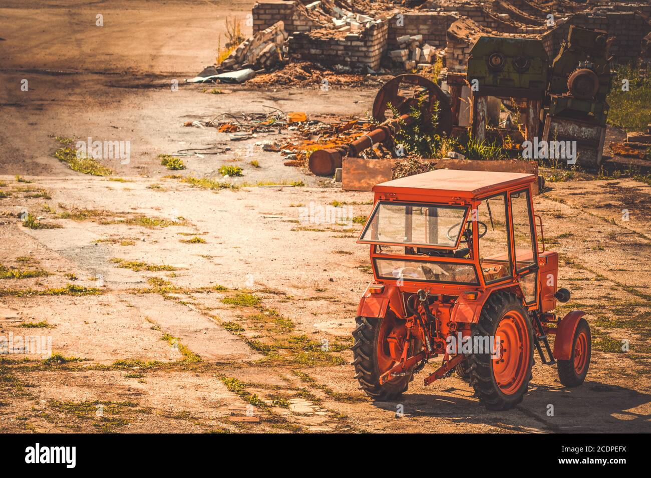 Trattore rosso parcheggiato nel cortile di una fabbrica abbandonata Foto Stock