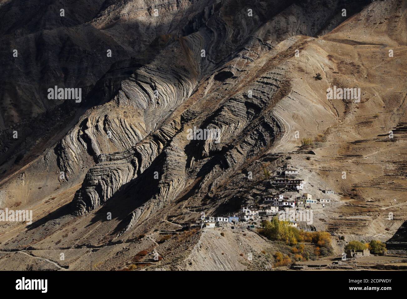 Un remoto villaggio lontano su un pendio di collina con strane texture, luce e ombra, poca vegetazione in India Foto Stock