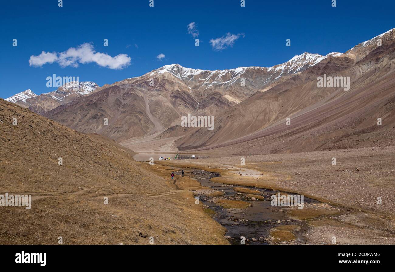 Due turisti camminano verso Chandra tal seguendo uno stretto ruscello in una giornata limpida ad un'altitudine di 4250 m. Foto Stock
