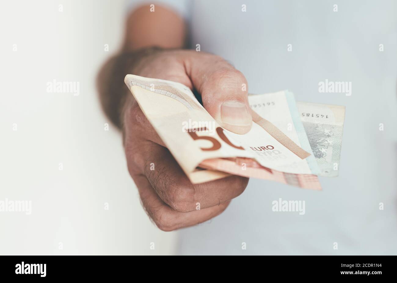 primo piano di mano di caucasico che offre o consegna denaro a qualcun altro Foto Stock