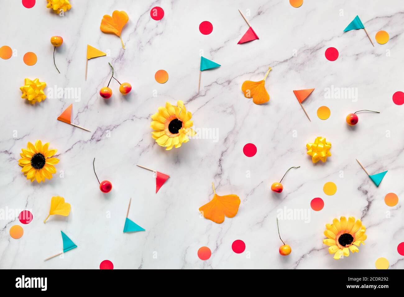 Astratto autunno sfondo stagionale con fiori gialli, foglie di gingko autunno, confetti di carta e bandiere toothpick. Piatto su tavolo in marmo bianco. Foto Stock