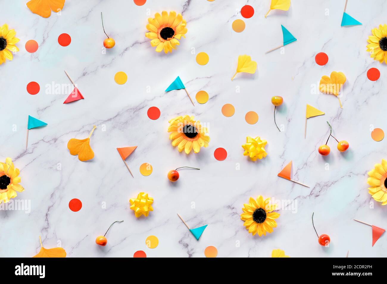 Foglie autunnali di gingko, confetti di carta e bandiere di stuzzicadenti. Piatto su tavolo in marmo bianco. Autunno astratto sfondo stagionale con fiori gialli, Foto Stock