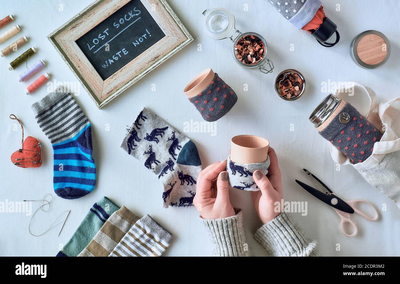 Zero rifiuti domestici. Facendo tazza di bambù e manica dell'ombrello dai calzini vaganti. Calze non abbinate orfane. Piatto posato su tovaglia tessile. Foto Stock