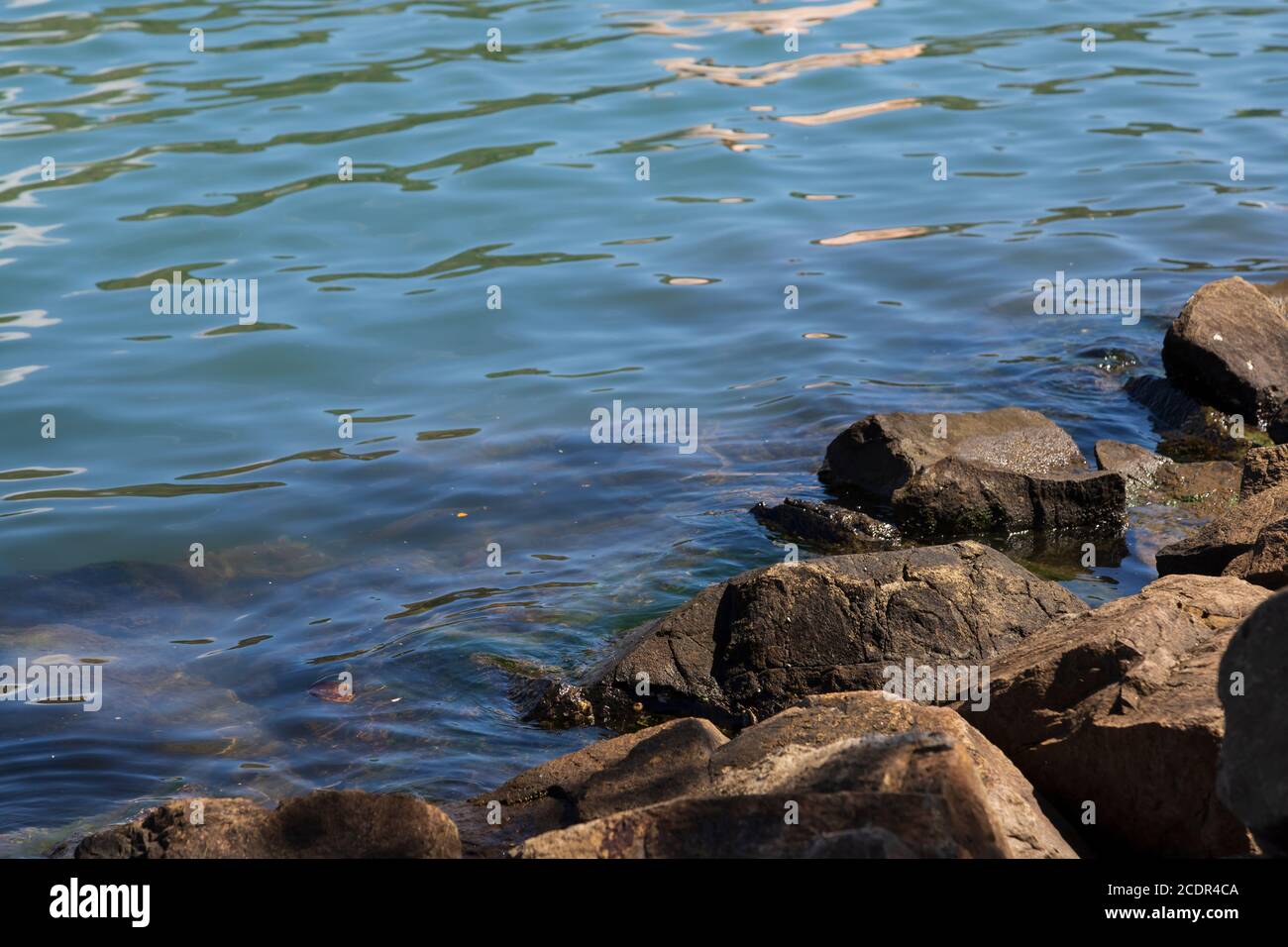 increspature sull'acqua di mare e rocce sul lato Foto Stock