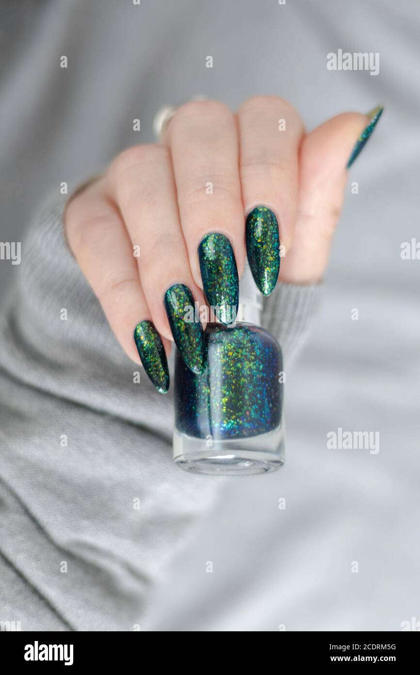 Mano della donna con unghie lunghe e manicure verde con bottiglie di smalto  Foto stock - Alamy