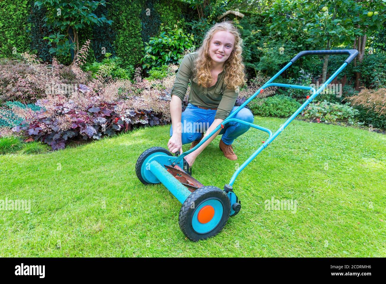 Giovane donna caucasica che ripara il rasaerba in giardino Foto Stock
