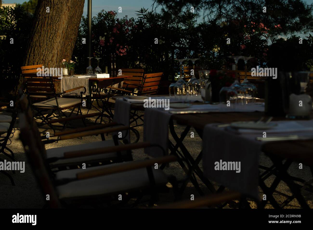 Un tavolo da pranzo e' bagnato dalla luce del tramonto in un ristorante costiero prima che la folla di cene arrivi. Foto Stock