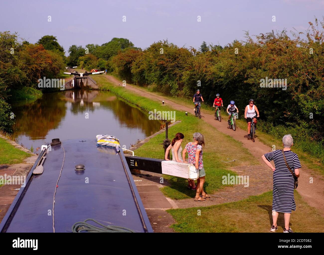 La vita sul Worcester e sul canale di Birmingham mentre una famiglia pedalando sull'alzaia passa una barca stretta che passa attraverso una serratura. Foto Stock